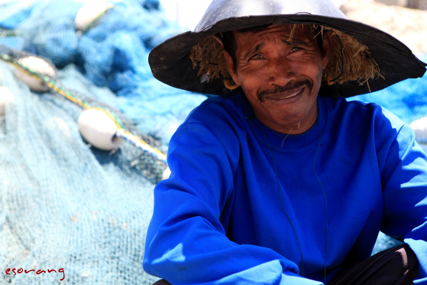 파란 옷을 입고 파란 그물을 손질 하는 아저씨